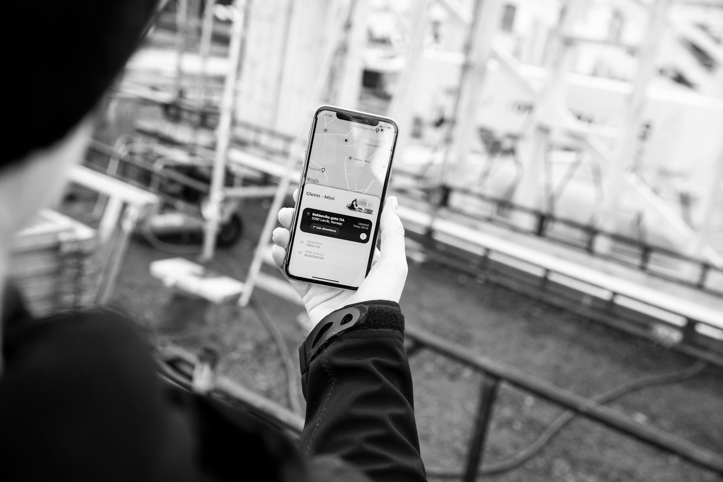 Man holding a phone on construction site with tracking on the screen