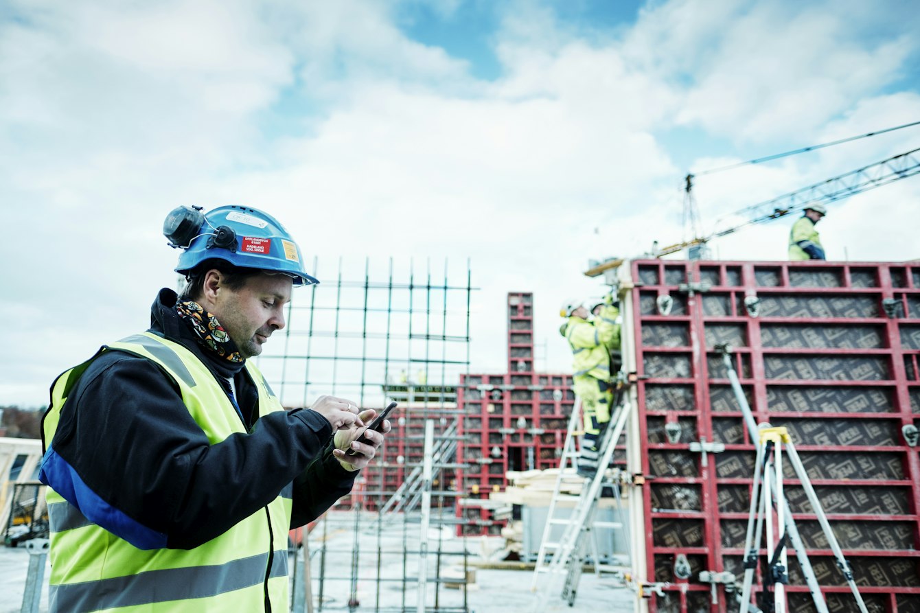 Man in high vis and hard hat on phone managing building site