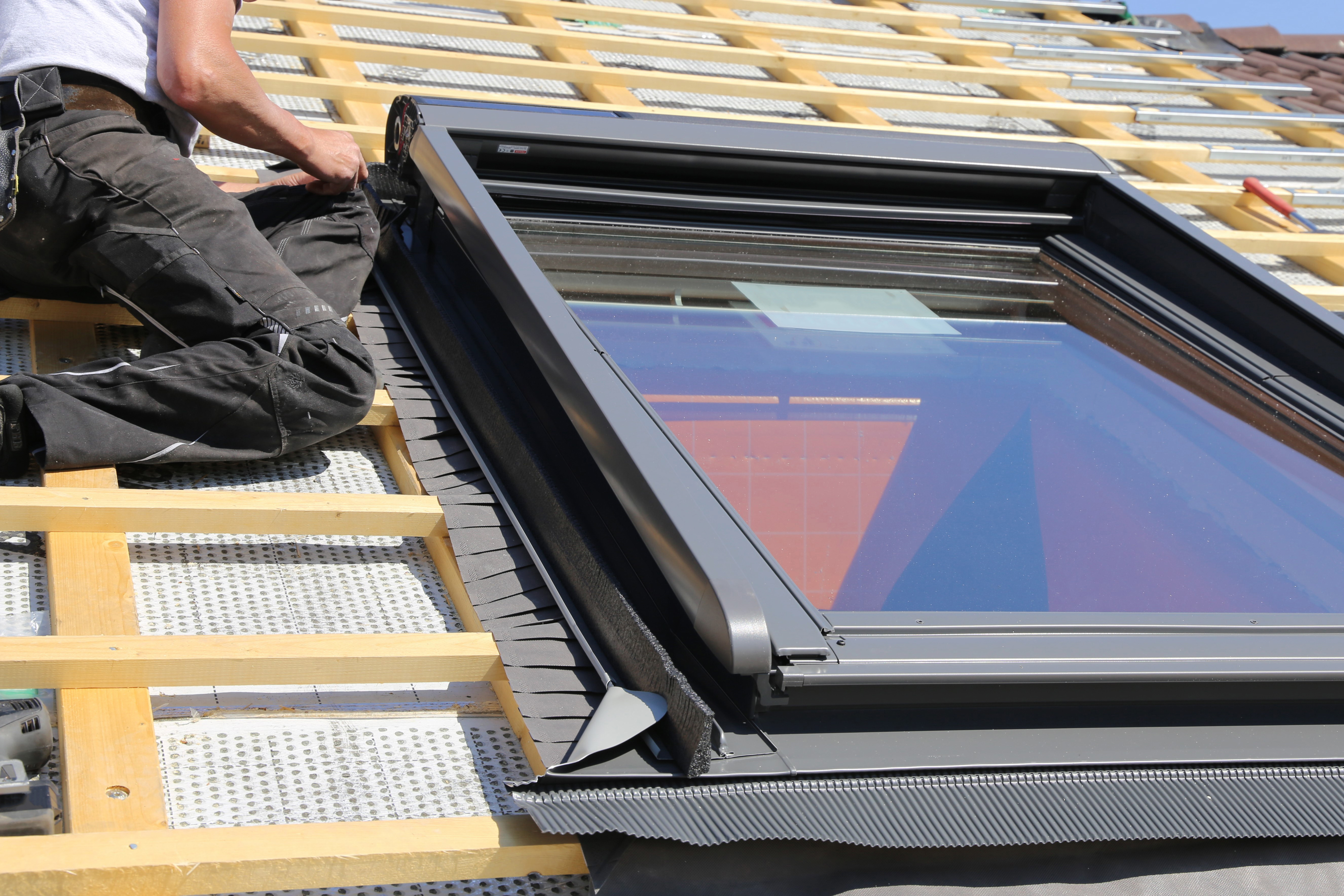 Man on roof fitting skylight window