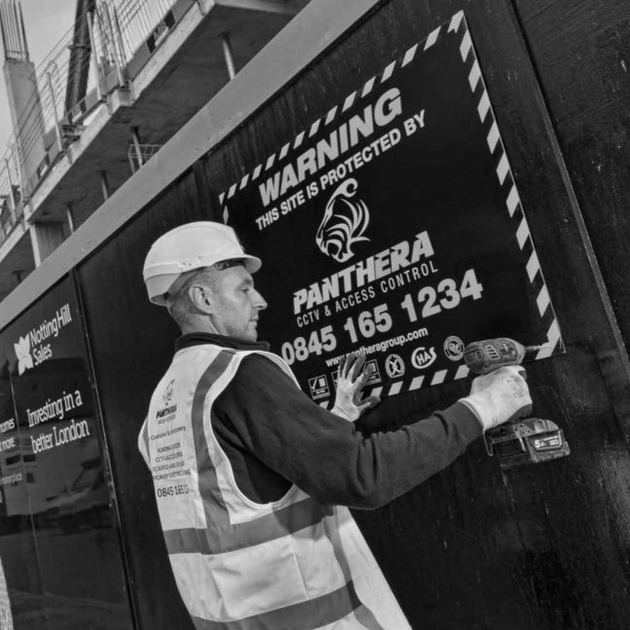 Man working on construction site putting up Panthera sign