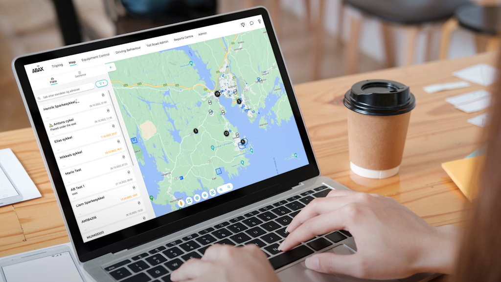 Person on laptop with coffee cup showing ABAX interface map