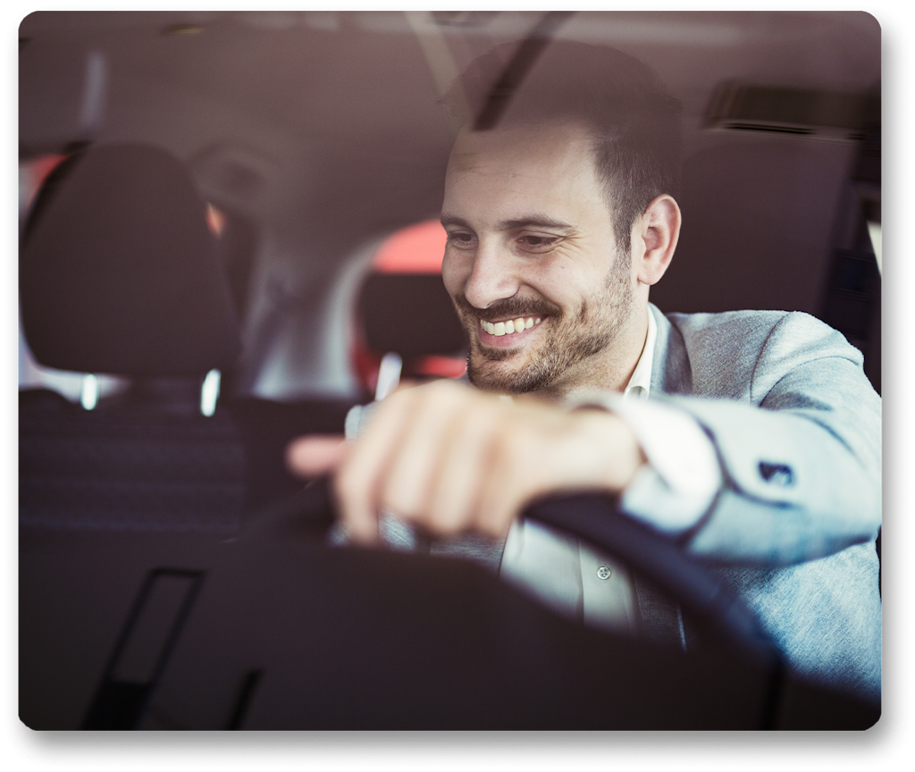 Man in car smiling with hand on stearing wheel
