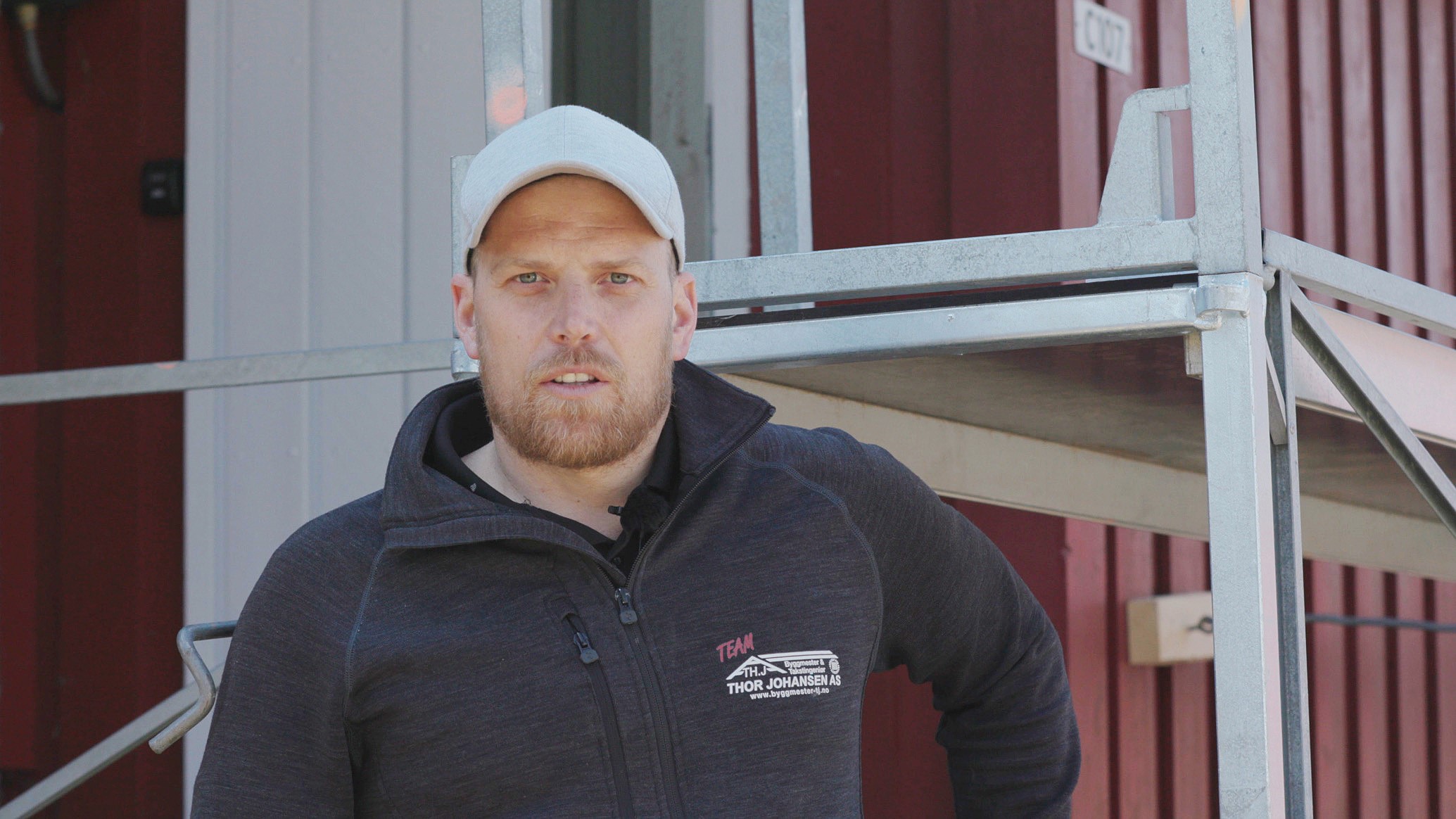 builder in front of scaffholding and red house