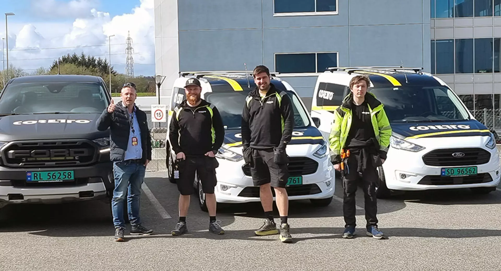 four men in front of work vans smiling and doing thumbs up