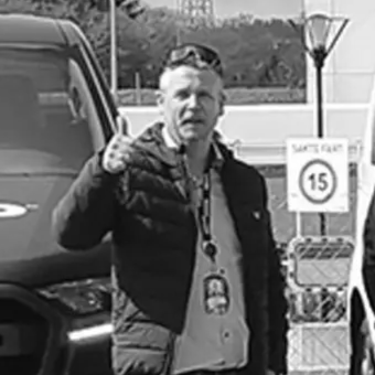 Man in front of work vans doing thumbs up black and white