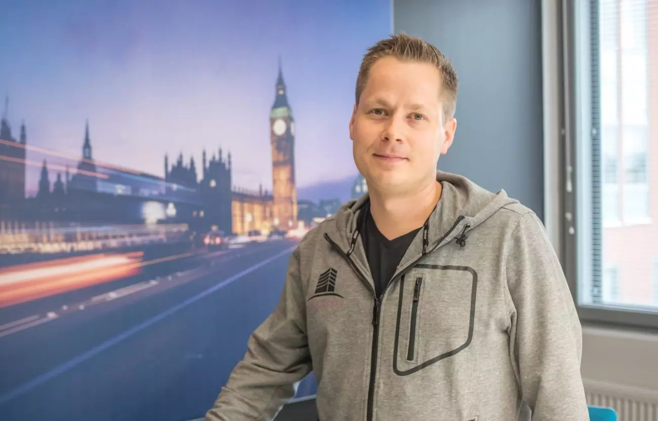 man in front of picture from london looking at the camera