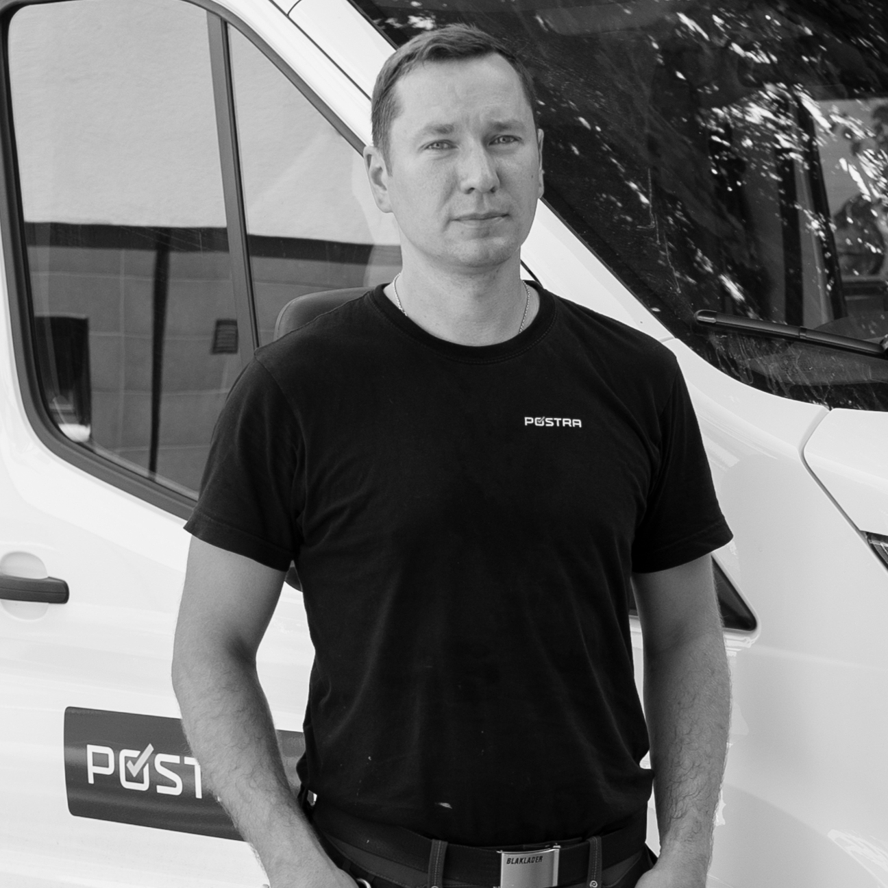 Man in front of work van in black tee