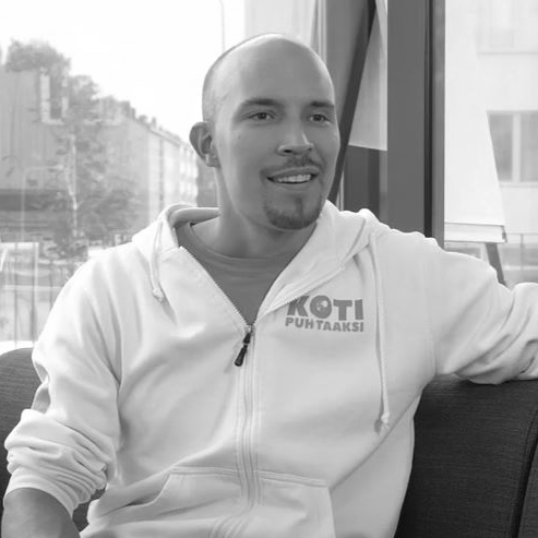 man sitting on a couch in front of window smiling black and white