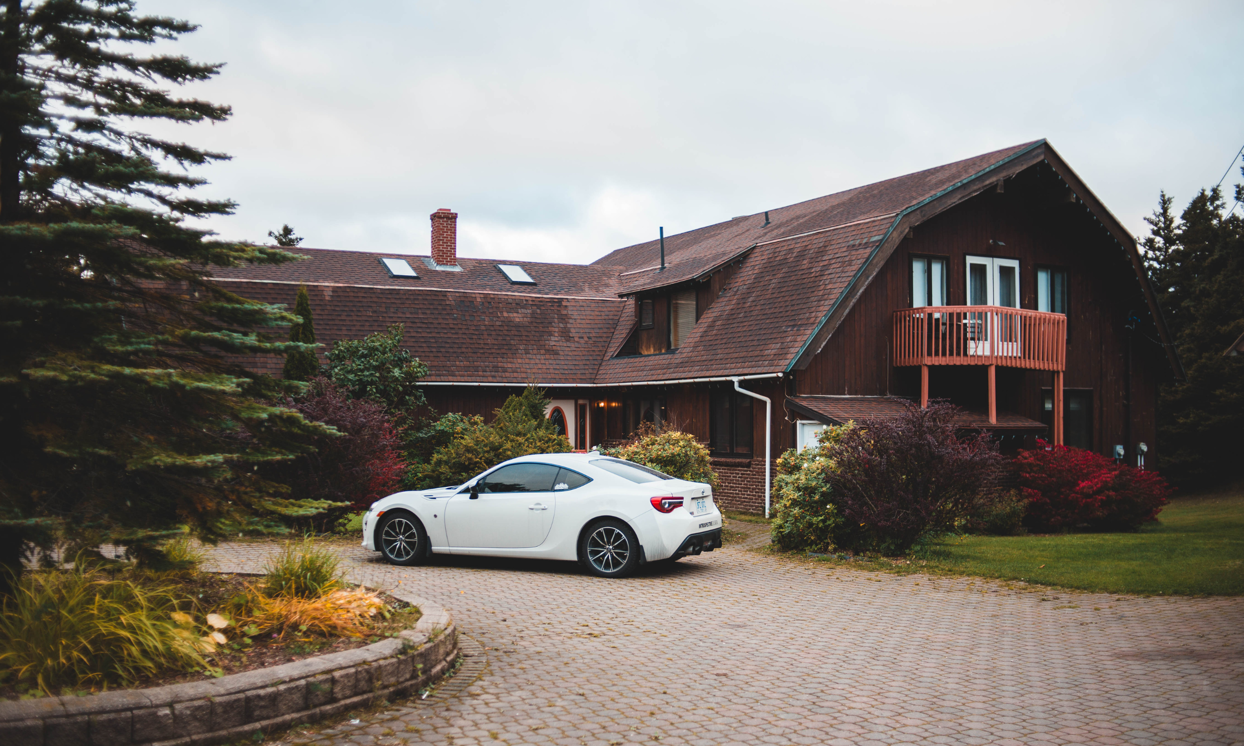white car in front of brown wooden house