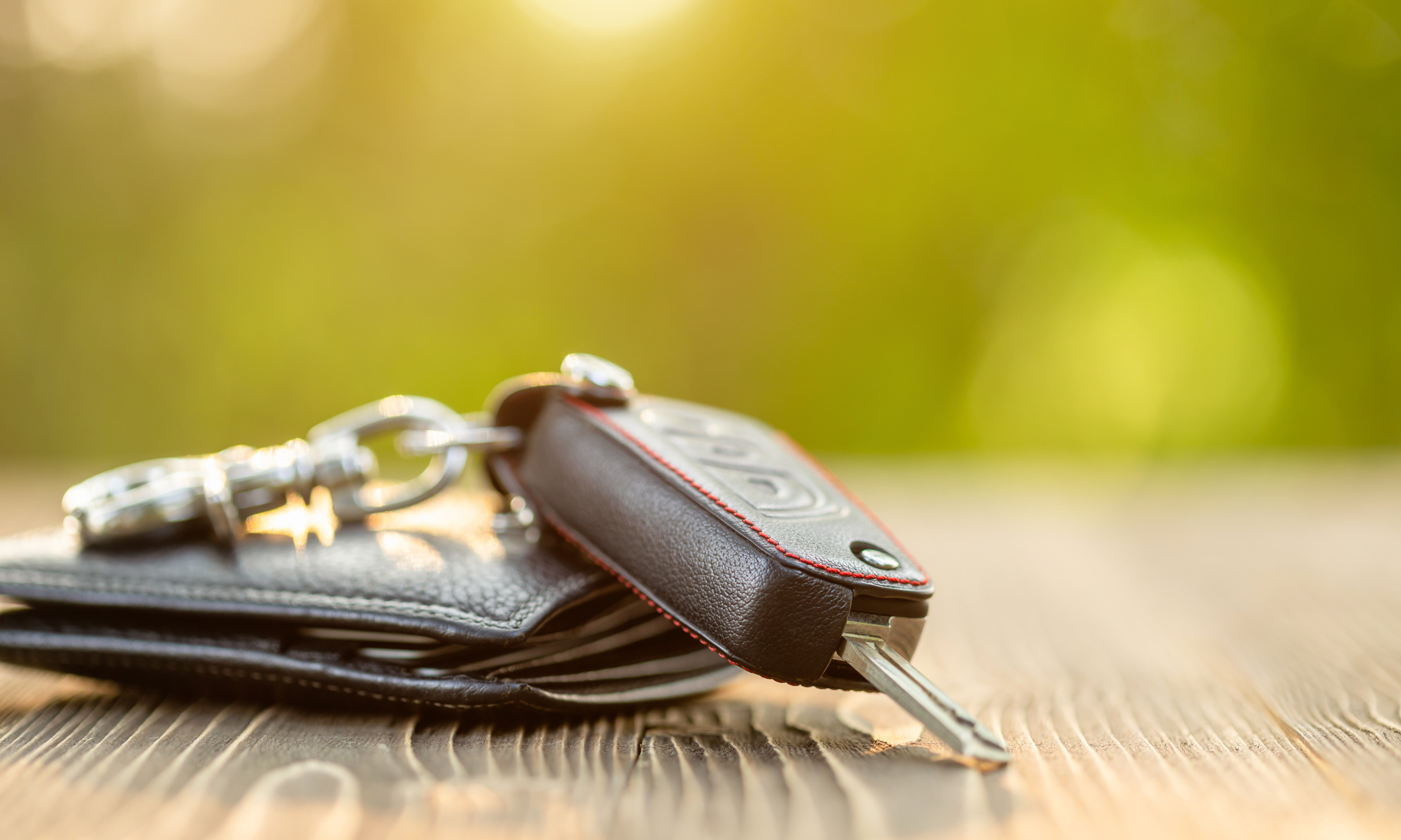 car keys on table outside with greenry in the background