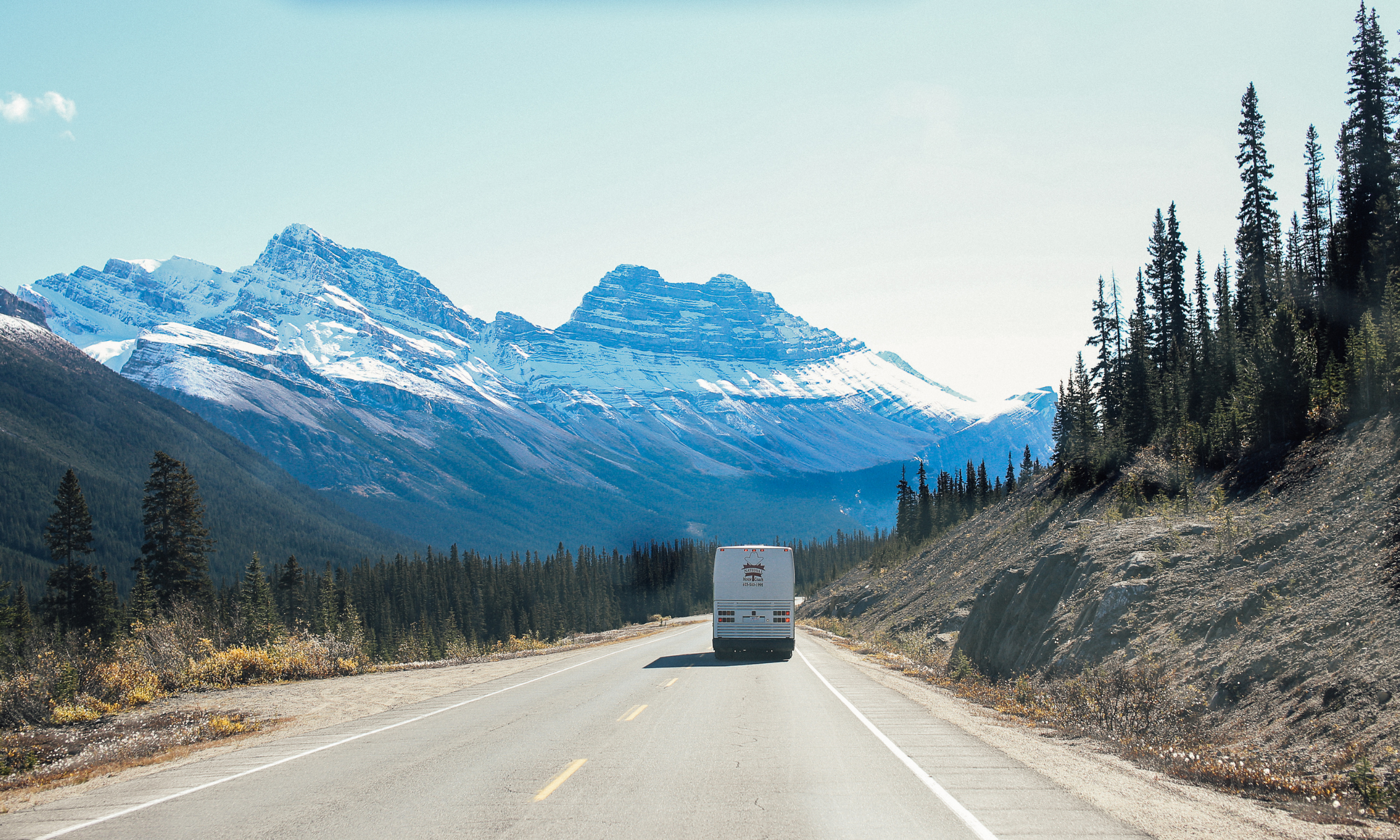 back of white van on road with mountains in the background