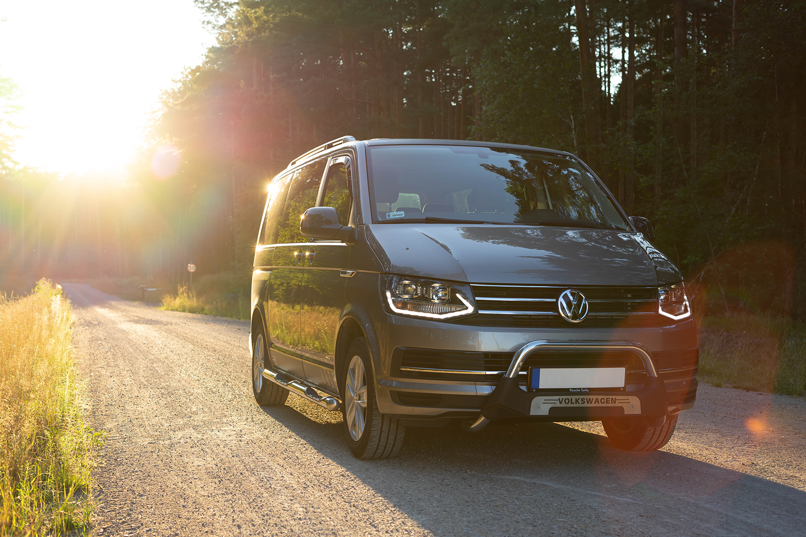 volkswagen car driving on road with sun shining behind