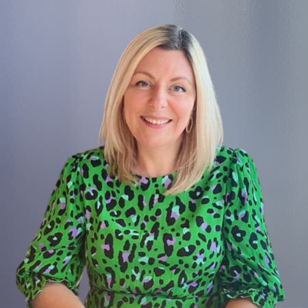 Blond woman in green leopard top smiling with blurred background