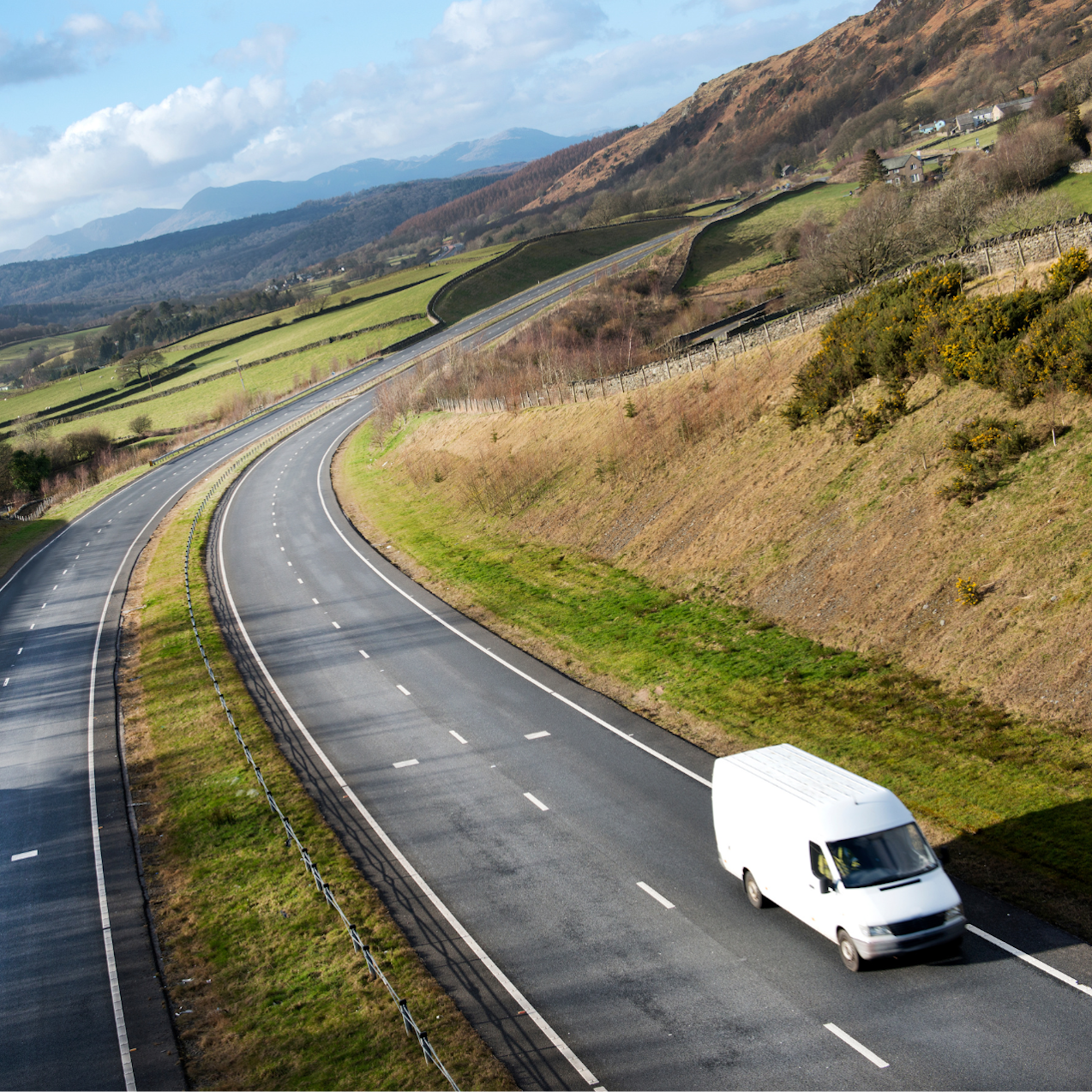 White van on dual carriageway with UK countryside in background