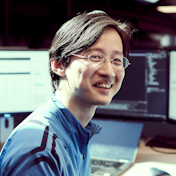 Man infront of computers smiling at camera