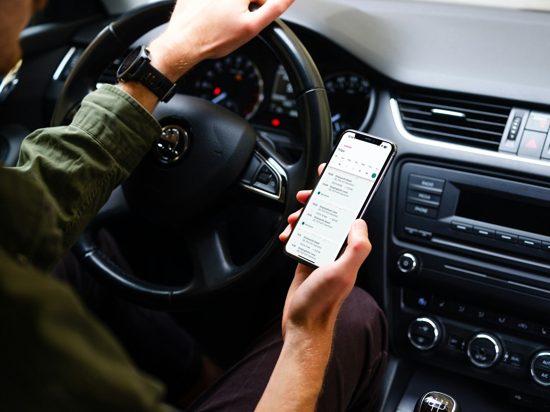 Føreren sidder stille i bilen og tjekker sporingssoftwaren på telefonen.