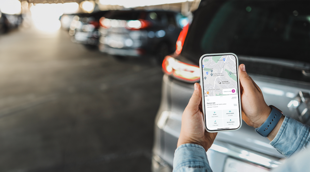Person on phone in car park looking at ABAX app with real time map on screen