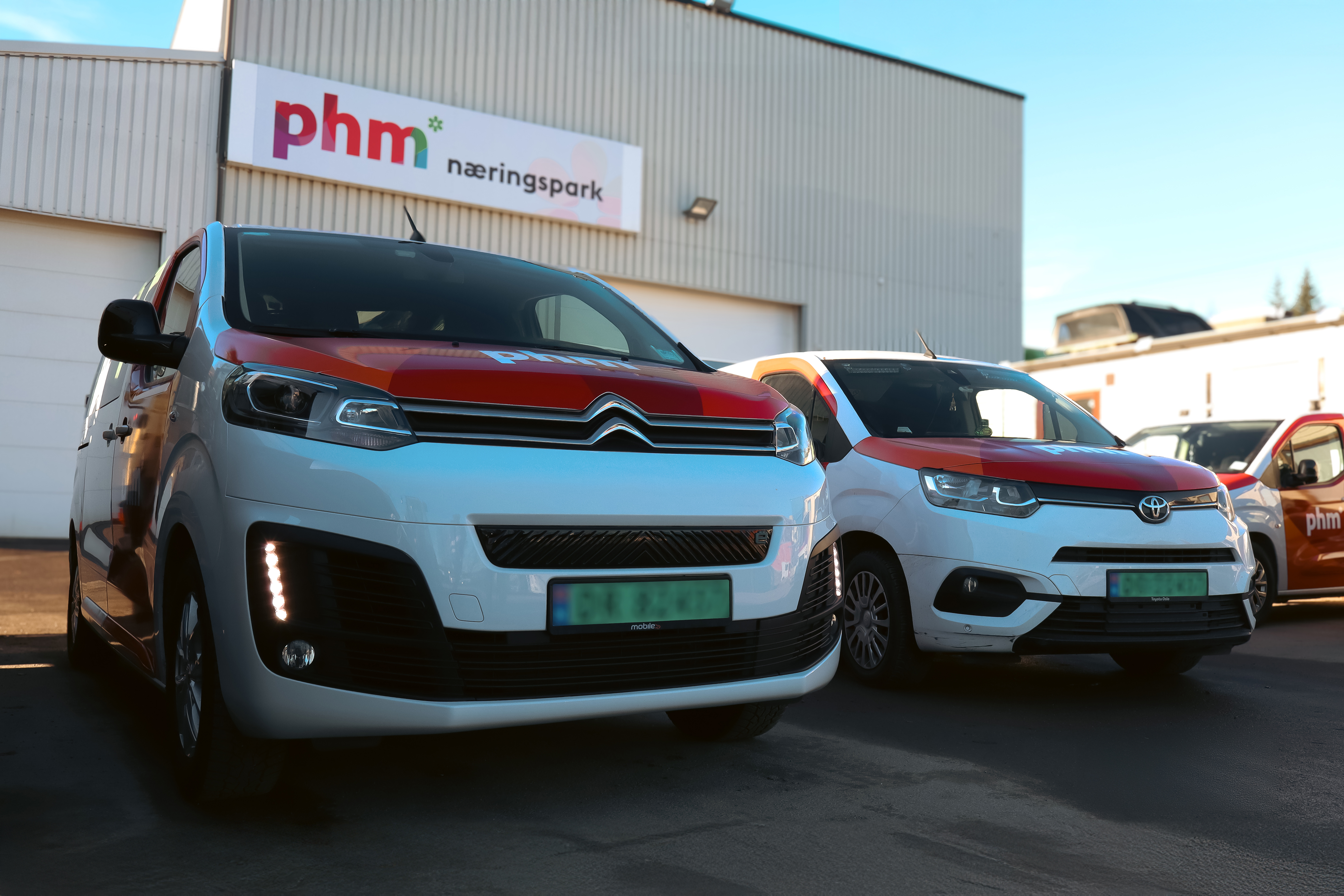 parkerte biler med PHM logo i bakgrunnen