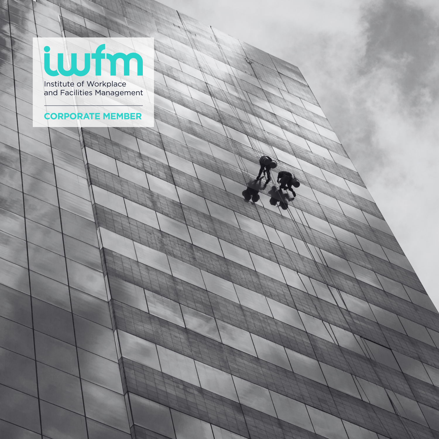 Skyscraper building with window cleaners abseiling and IWFM logo in blue