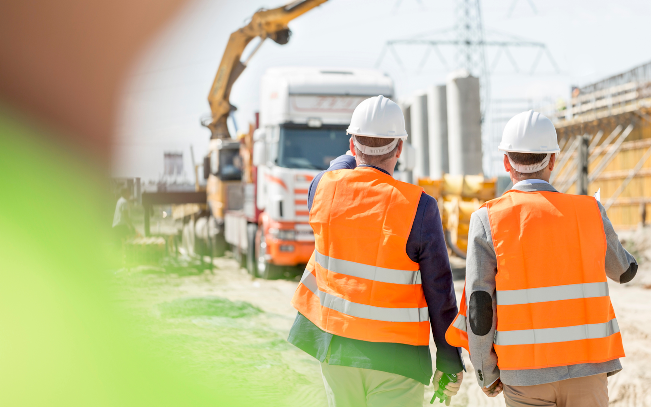 Two site managers in hi-vis and hard hats on a construction work site