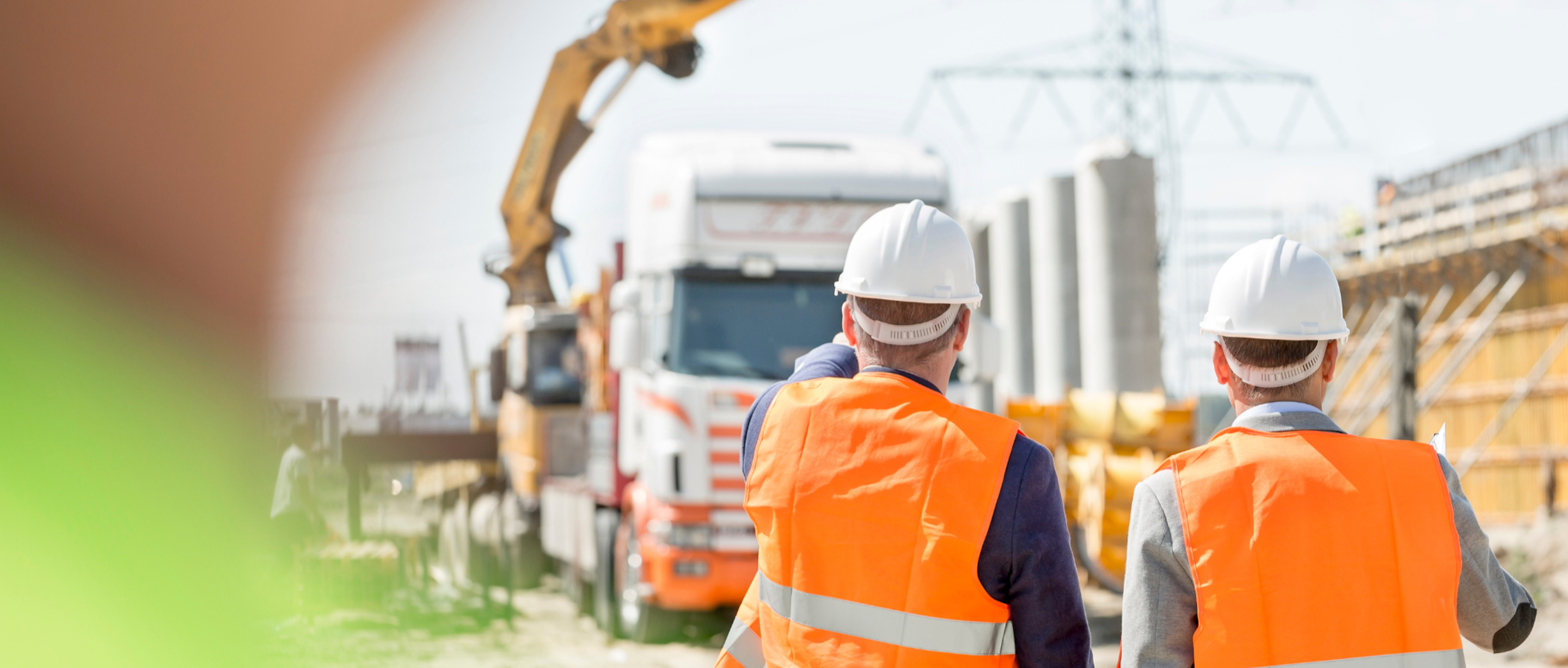 Two site managers in orange hi-vis and hard hats on a construction site