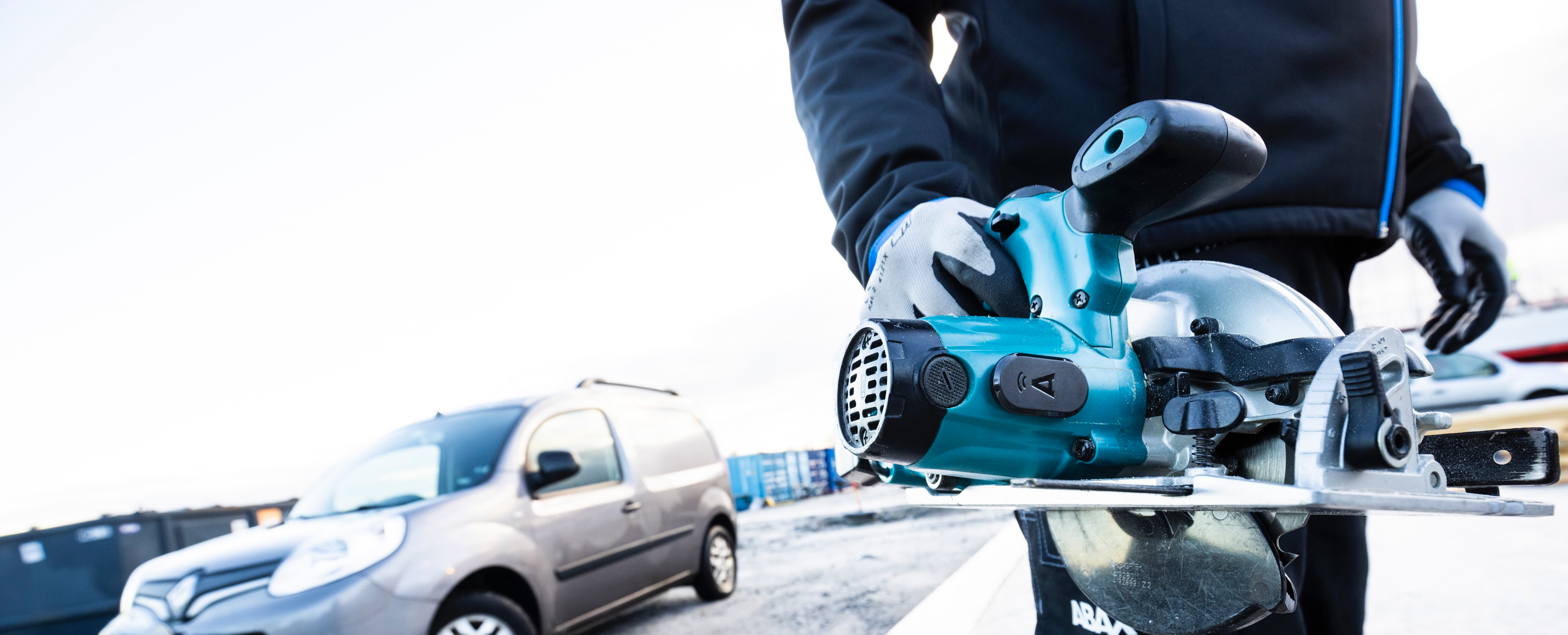 Hand held power tool with ABAX tracker on and car in background