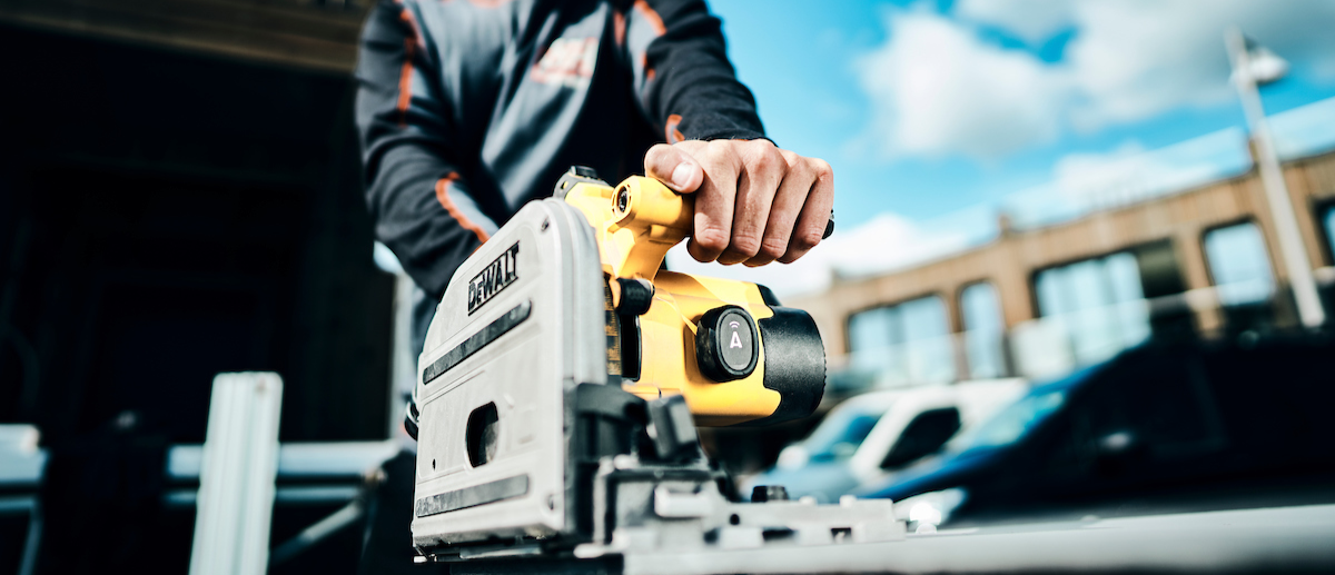 Workman using DeWalt tool in yellow and grey with ABAX tracker on it