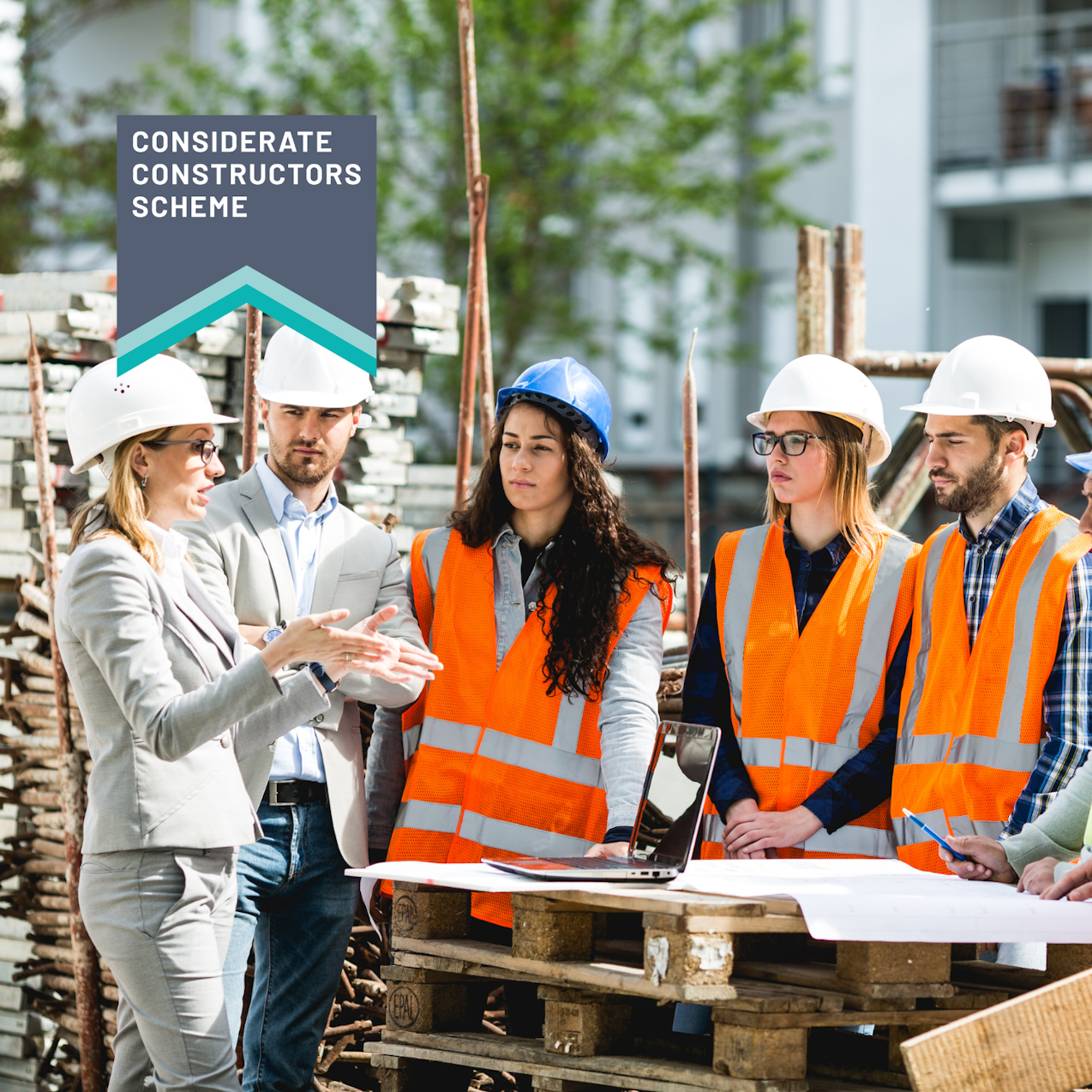 Construction workers in hard hats and high vis having a meeting outside