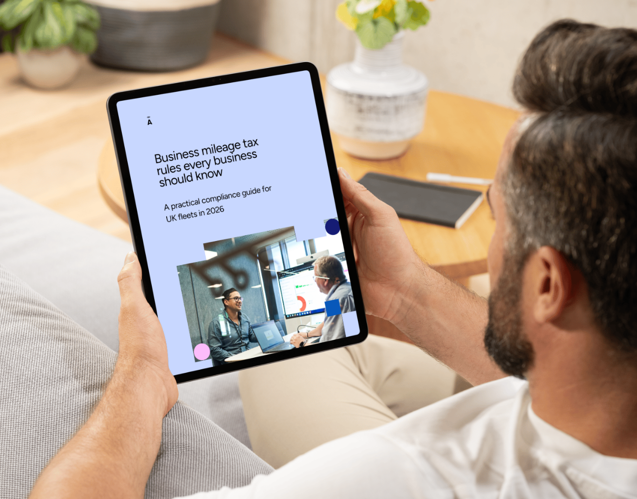 Man sat on sofa, holding tablet with whitepaper tax guide 2026 on the screen