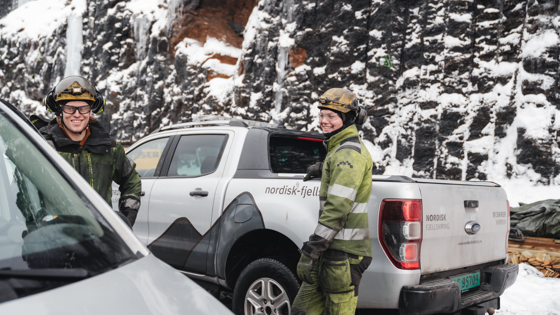 Nordisk Fjellsikring_to menn smiler ved siden av biler