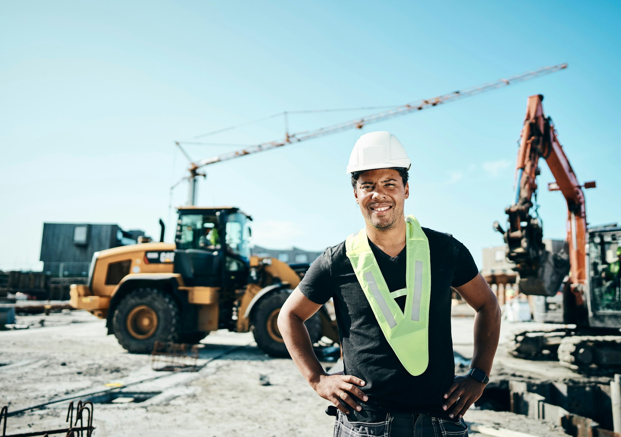 Construction worker standing in front of a site with heavy machinery