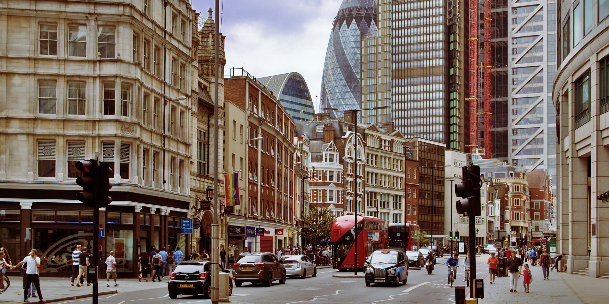 London street with Gherkin building in the background and red bus, vehicles on road