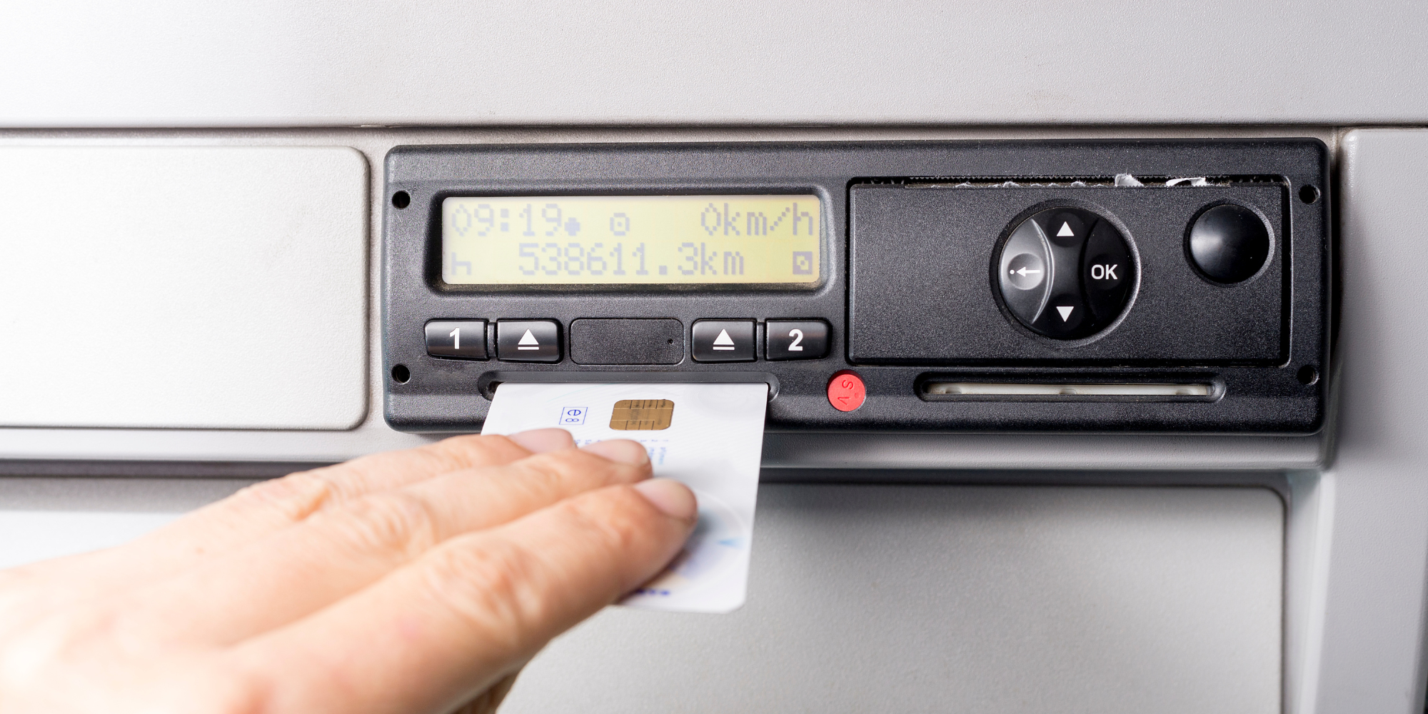 Digital tachograph and drivers hand inserting card into it.