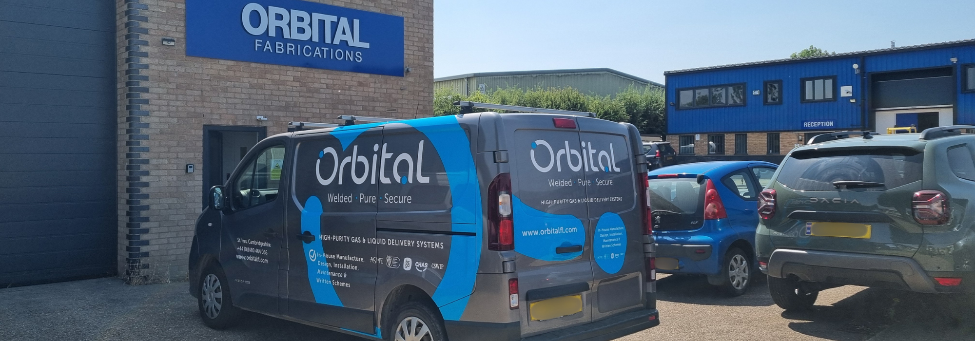 Orbital Fabrications office and manufacturing plant in St Ives. Van, blue building and staff car park.