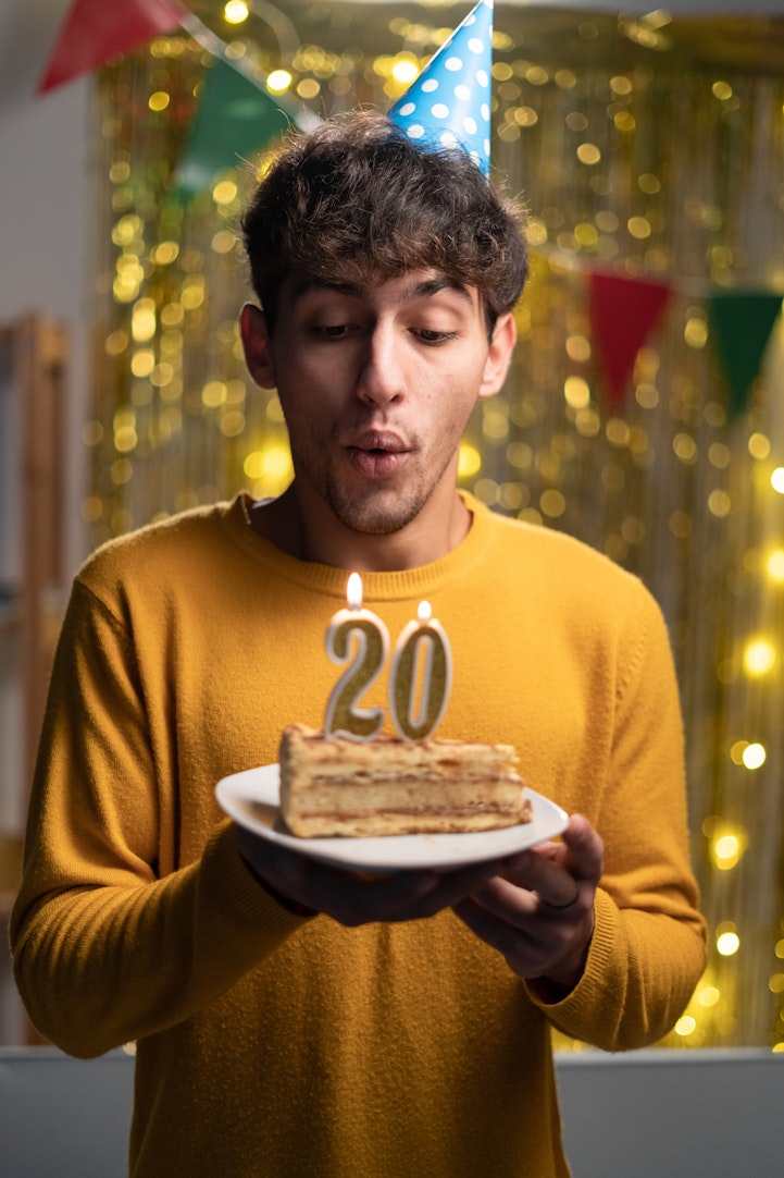 young man in yellow shirt with cake and a 20 on it
