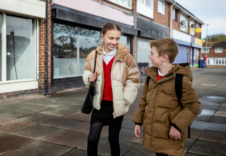 Two young people walking home next to shops