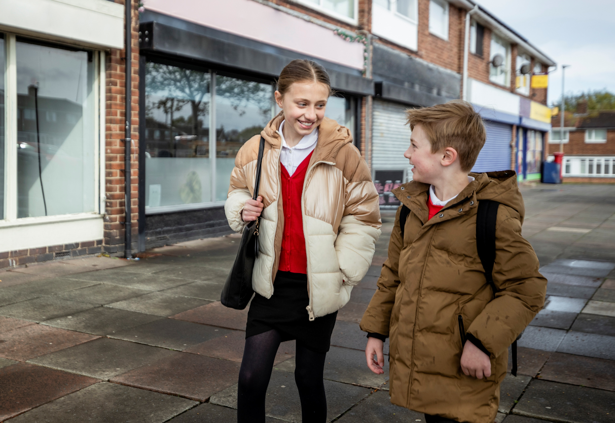 Two young people walking home next to shops