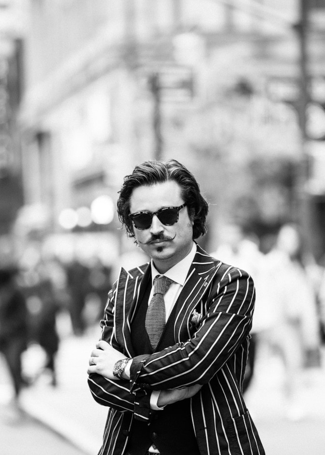 Mann mit Sonnenbrille und gestreiftem Jacket in schwarz weiß