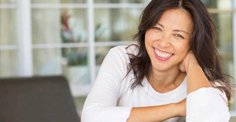 Woman Smiling with White Shirt Leaning on her Arm