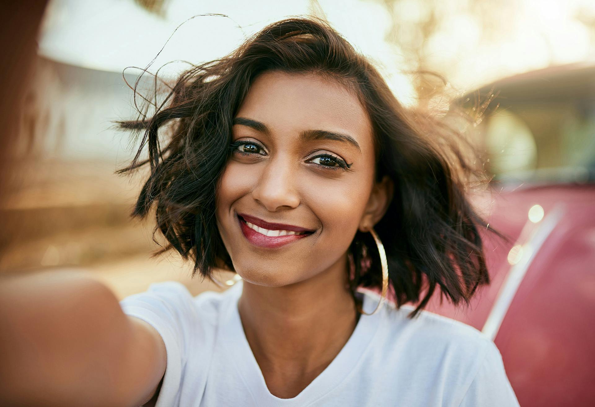 Selfie of a Woman with Short Hair in Front of a Red Car