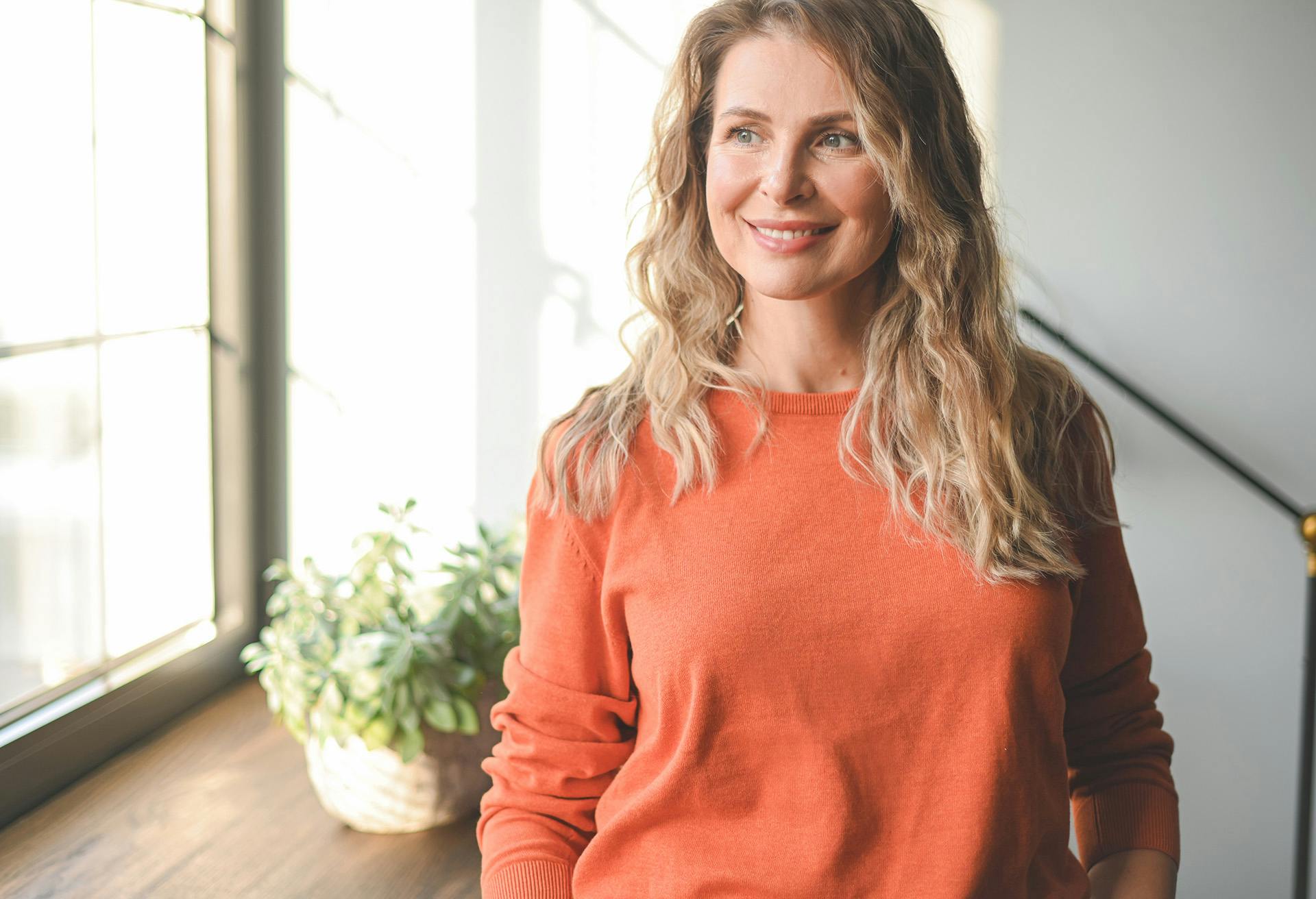 Woman with Orange Shirt looking out the Window