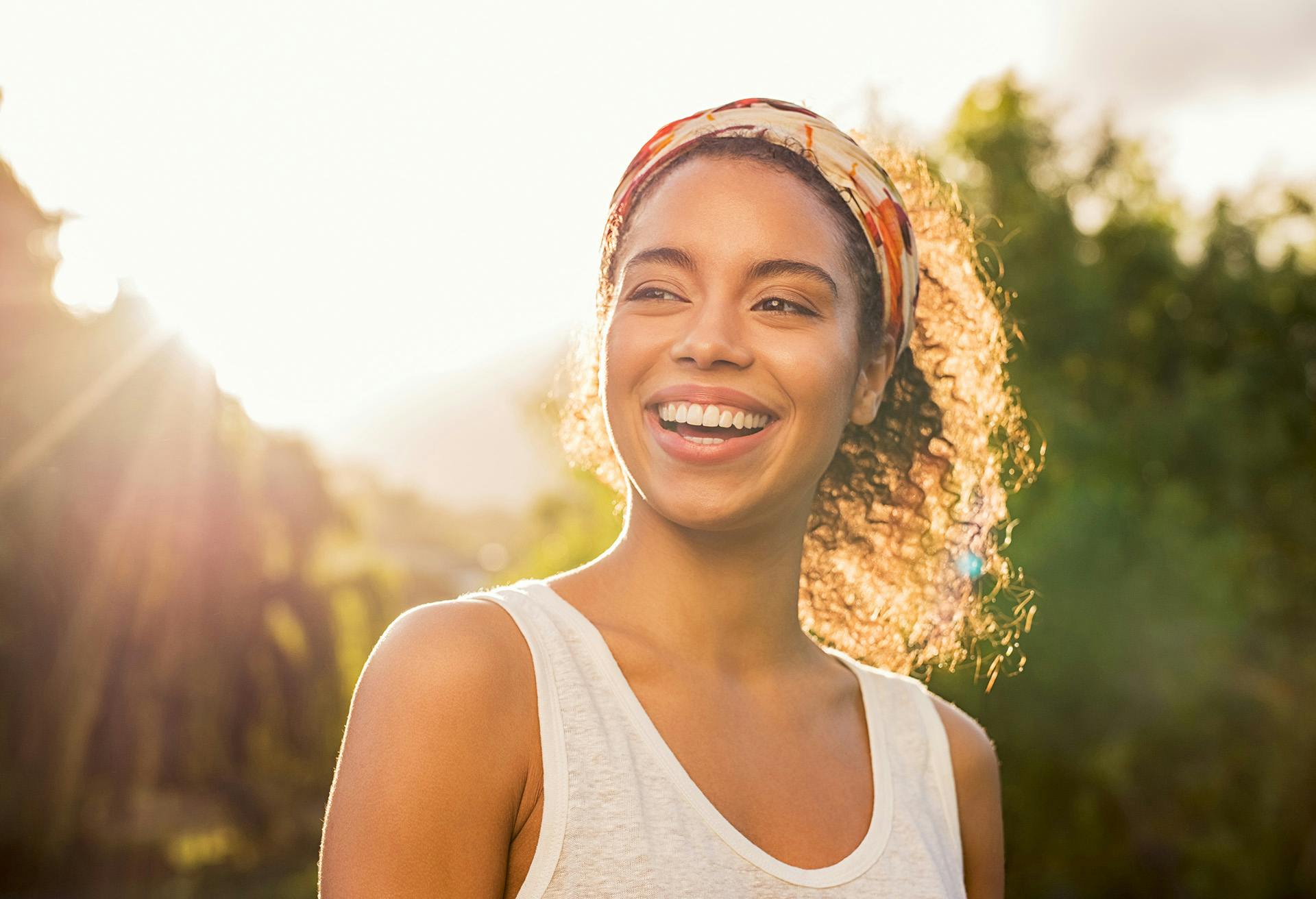 Woman smiling outside with the sun shining behind her