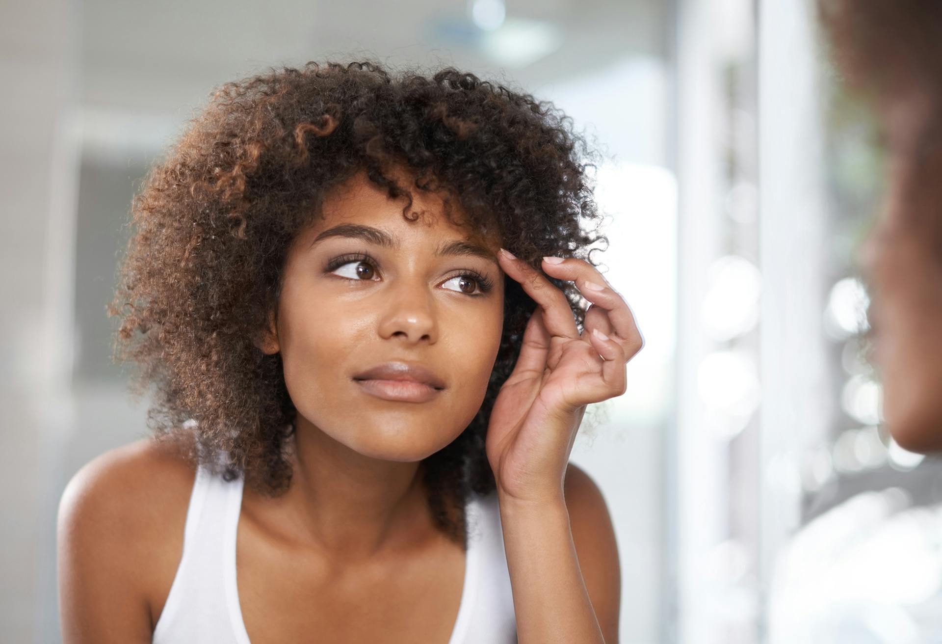 Woman Touching her Eyebrow in the Mirror