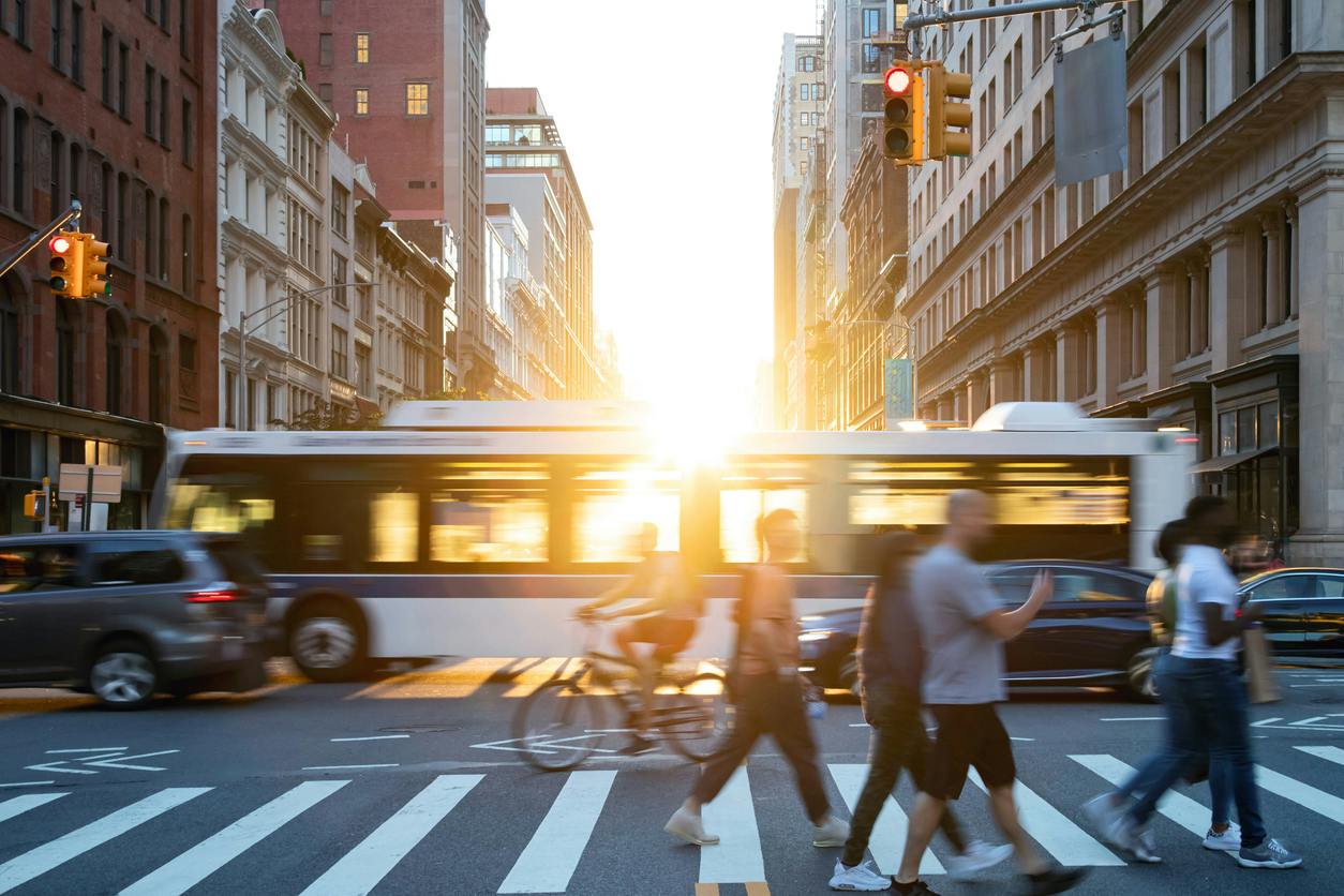 People, cars, bikes and buses traveling through a busy intersection on 5th Avenue and 23rd Street in New York City