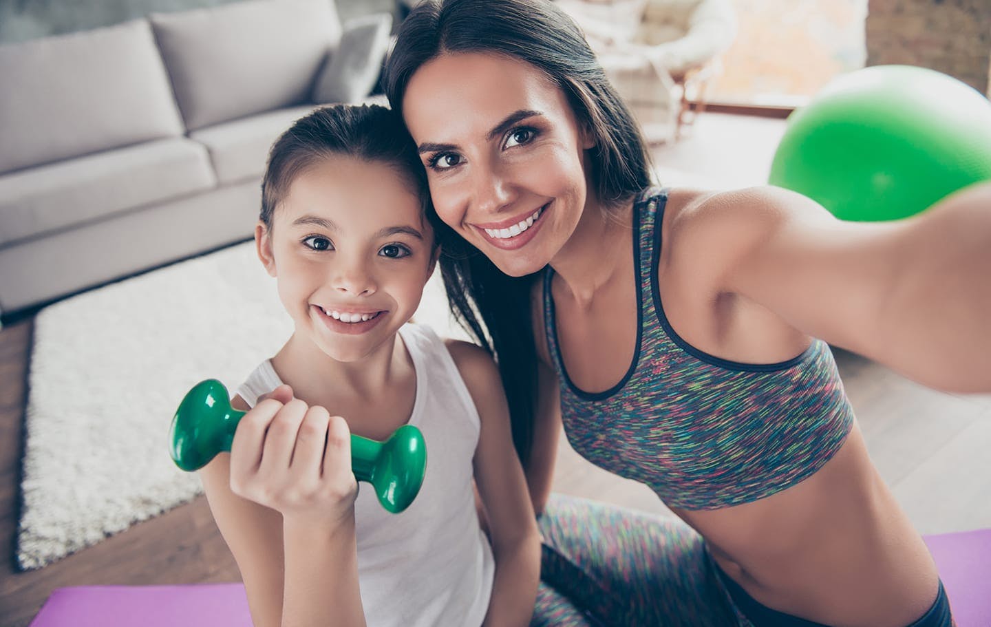 Mother and daughter posing for camera while carrying a small weight