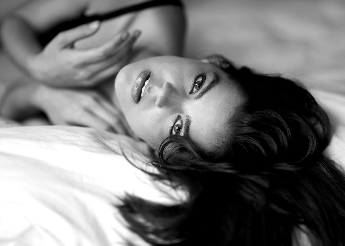 Black and white photo of a woman lying on a bed