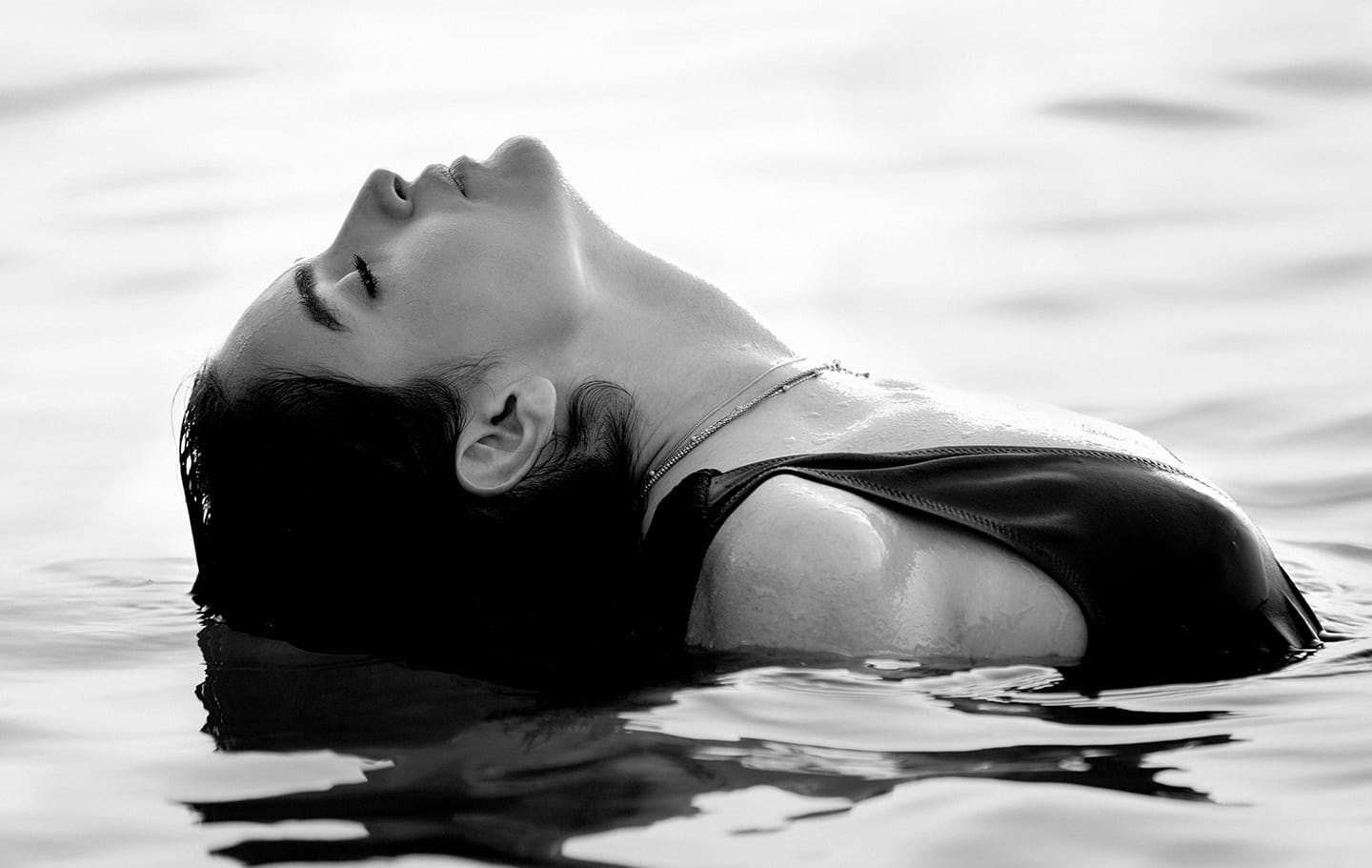 woman in a pool dipping head back