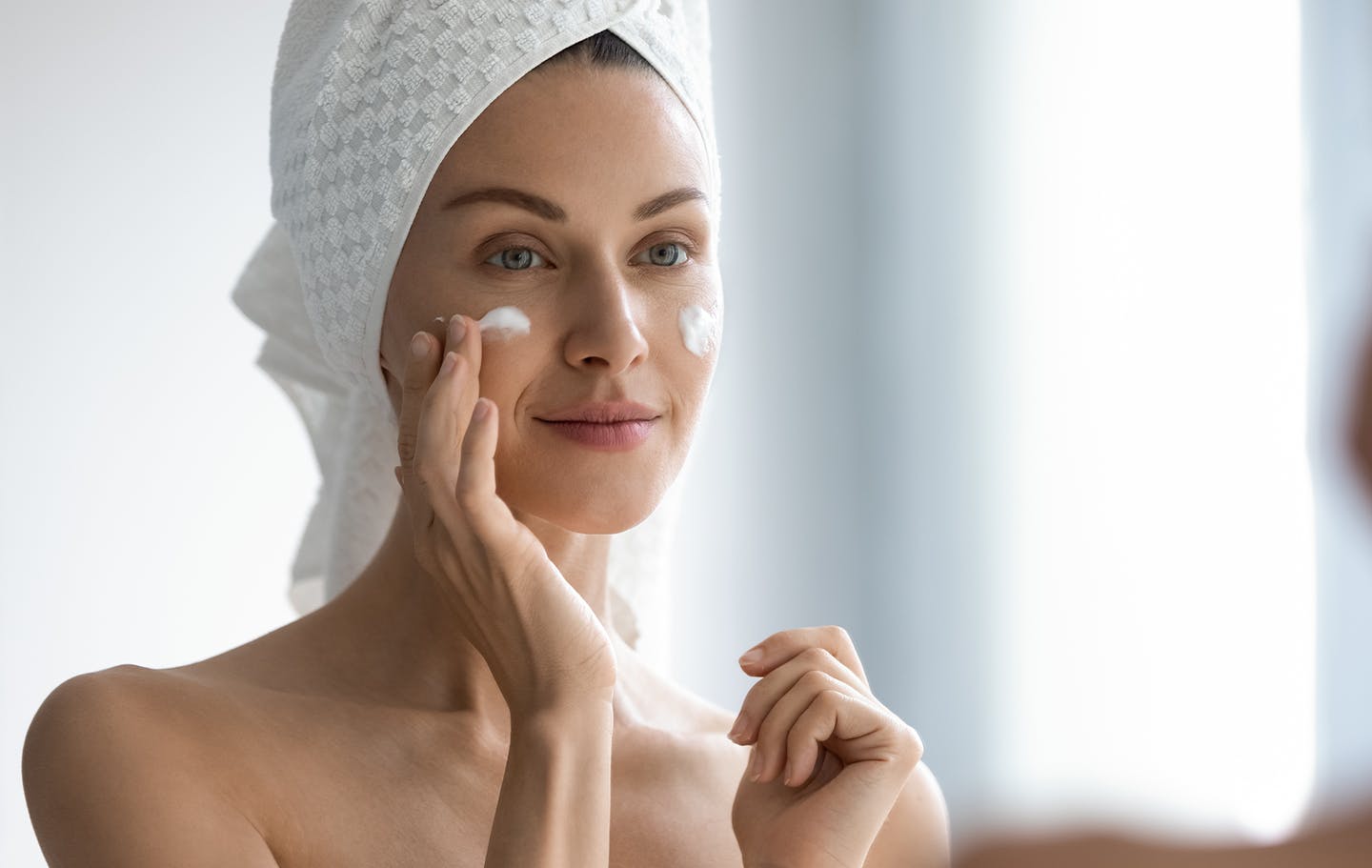 Woman applying creme to her cheeks.