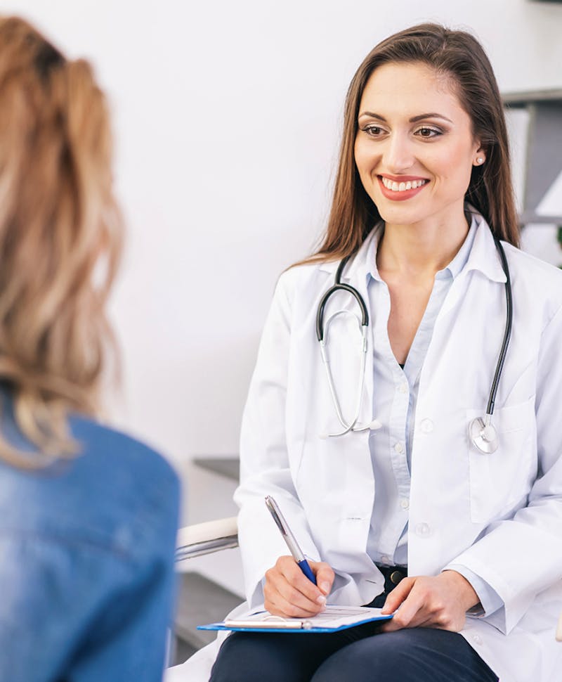 woman sitting in front of doctor with a white lab coat and a stethoscope