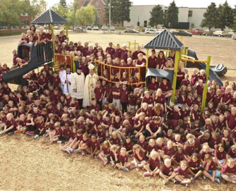 group of children posing for a picture in front of a playground